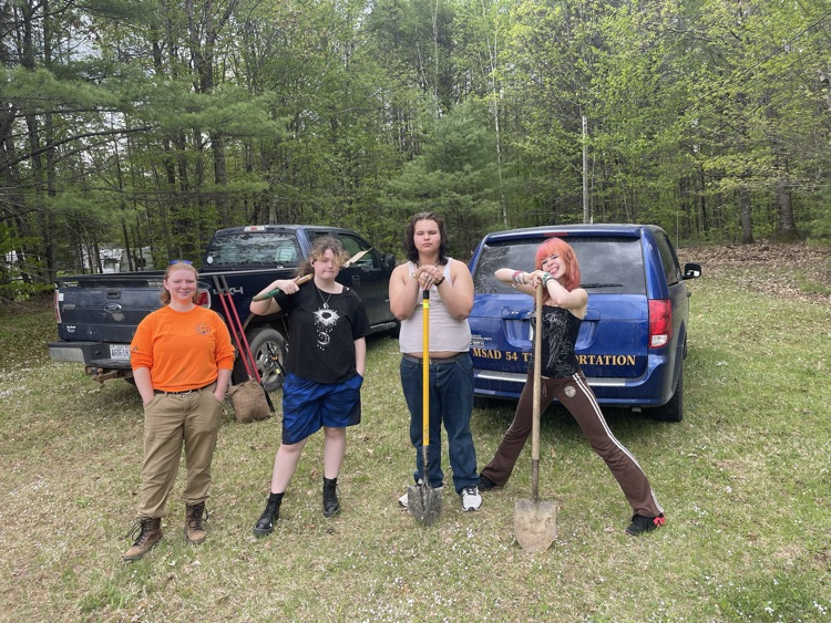 3 students and a staff holding shovels outside