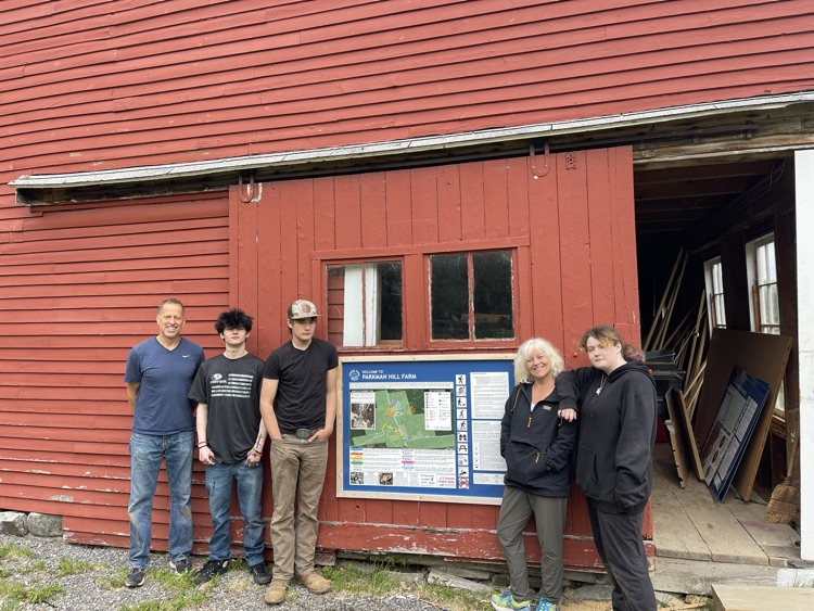 students and staff standing next to the newly mounted sign they put up