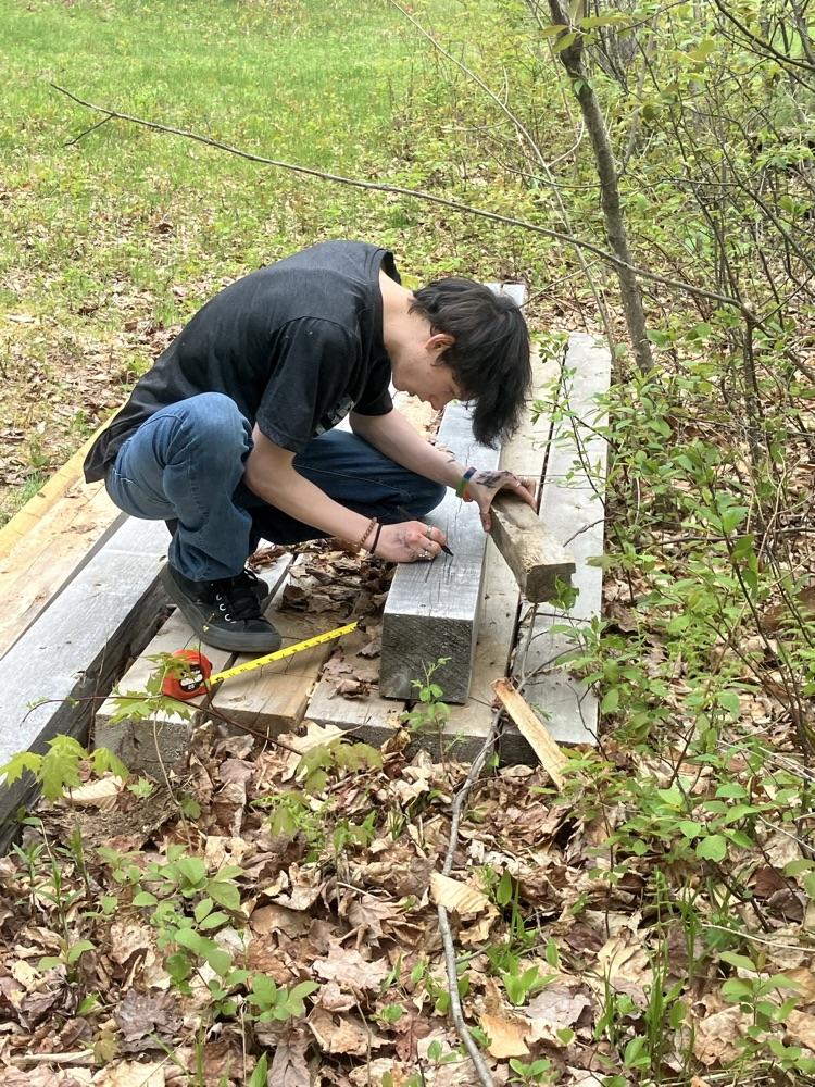 a student measuring the post for a sign to install