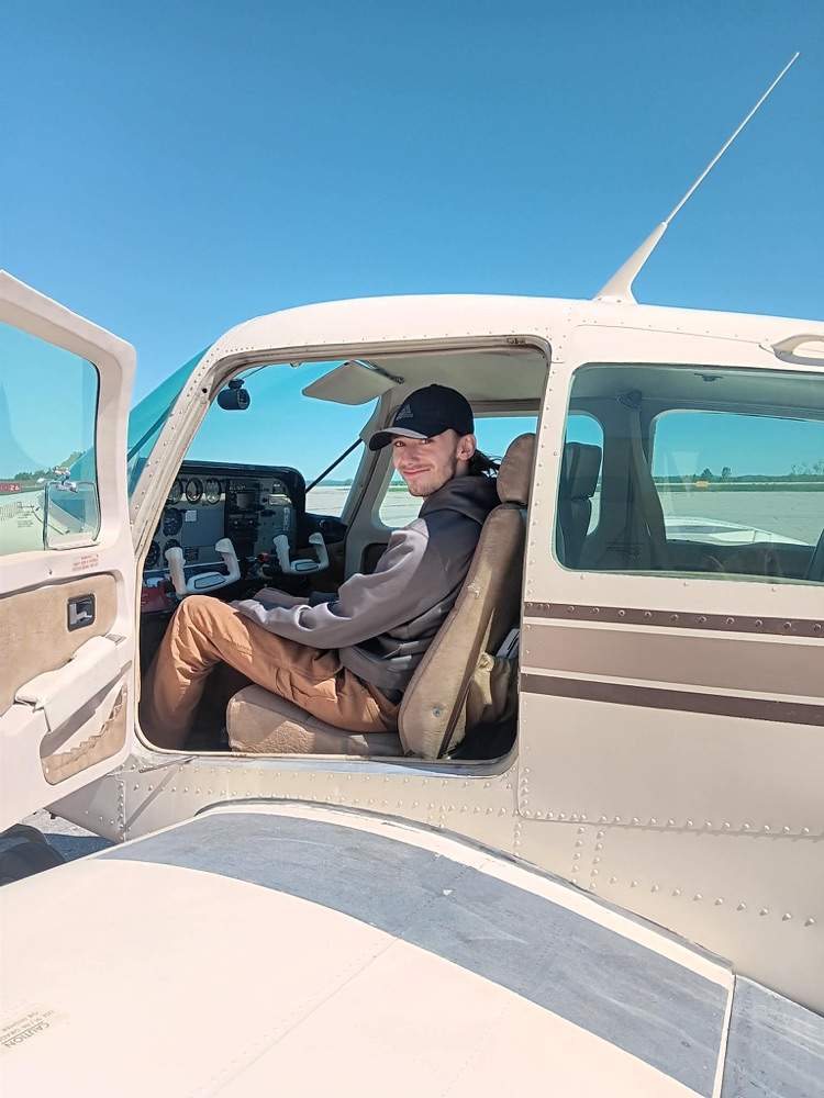 a male student sitting in the cock pit of a plane