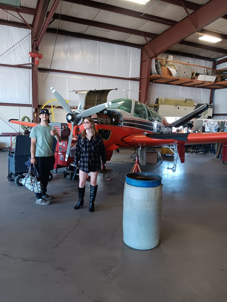 2 students in front of a small plane at the Augusta airport