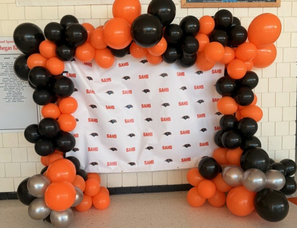 Black and orange balloon arch around a SAHS banner