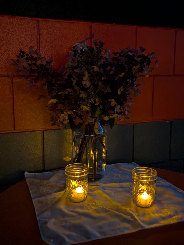 Flowers in a vase with lit candles around it