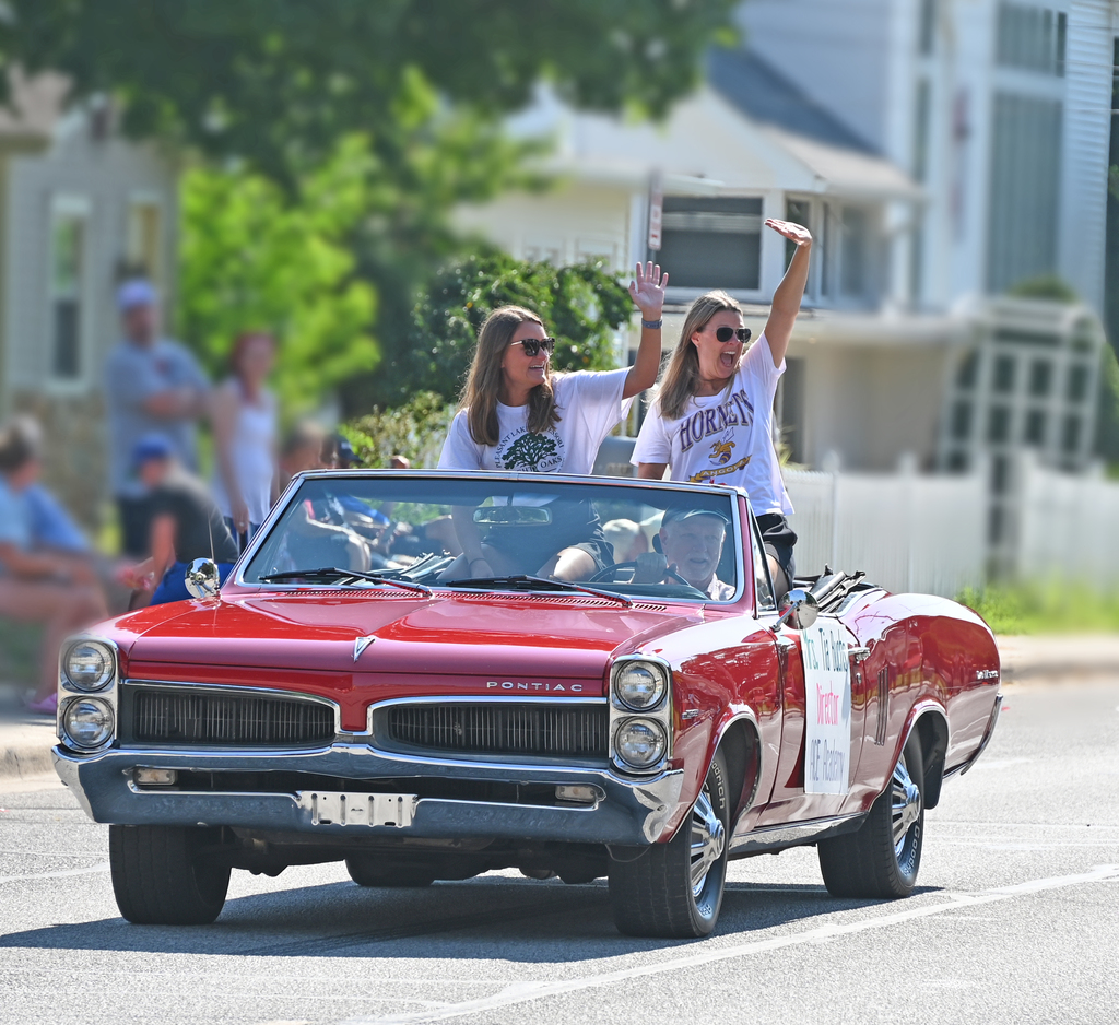 women waving from car in a parade