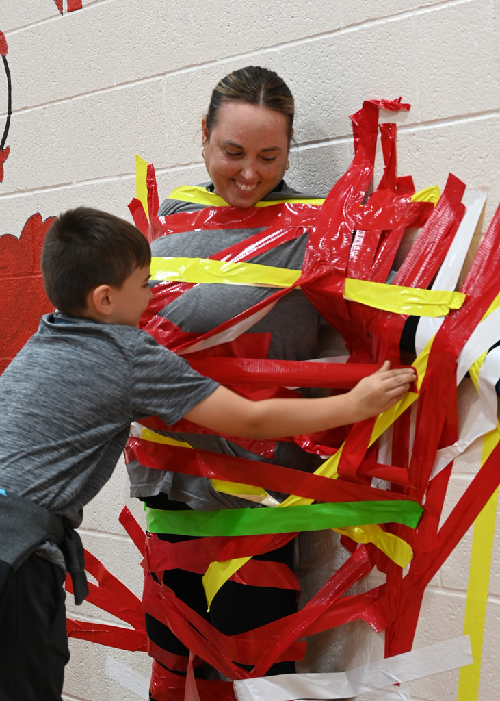adult being duct taped to wall by student