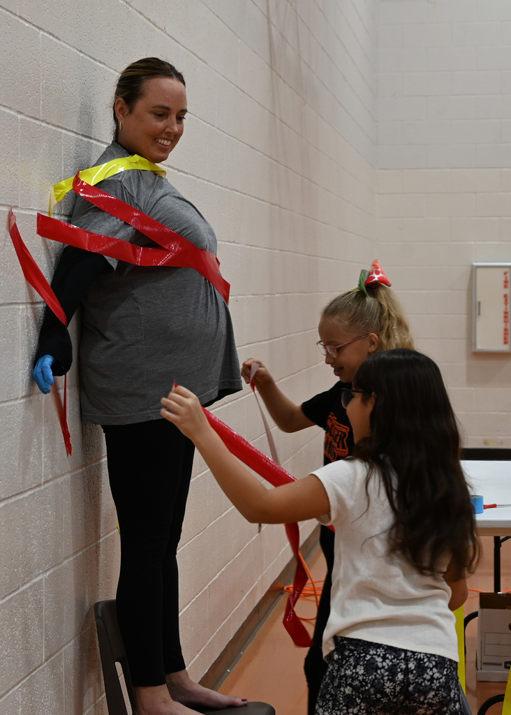 adult being duct taped to wall by students