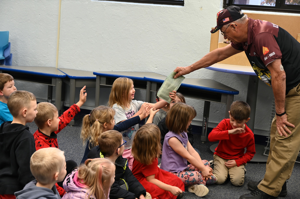 kids in group being shown package by veteran
