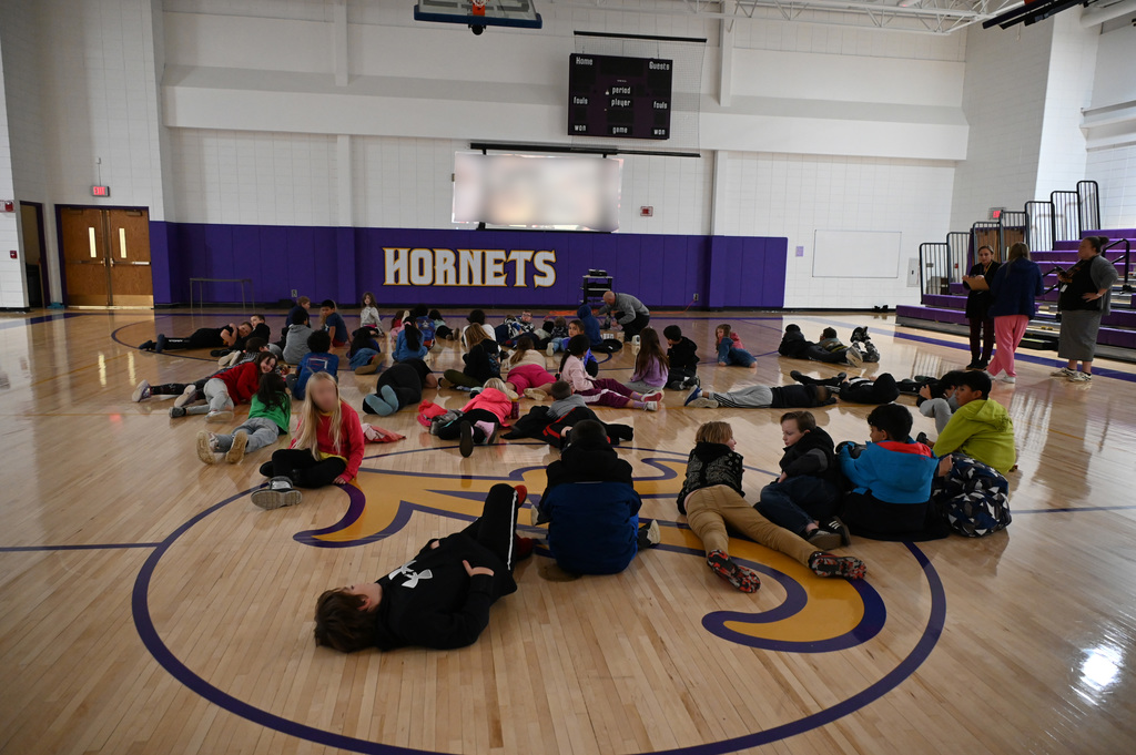 kids laying in a gym watching a movie
