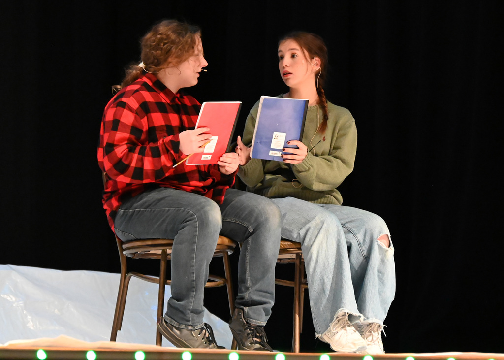 two people sitting in chairs holding notebooks