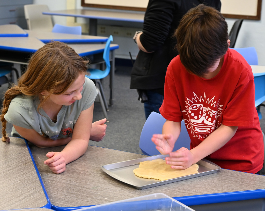 two childern making pie dough