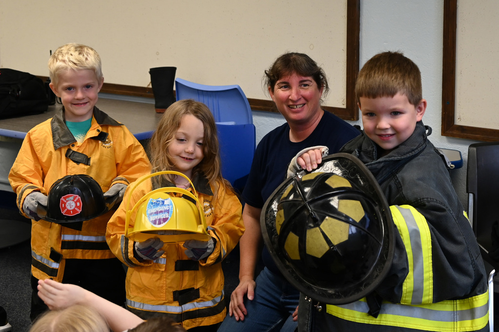 childern smiling at camera wearing fire gear