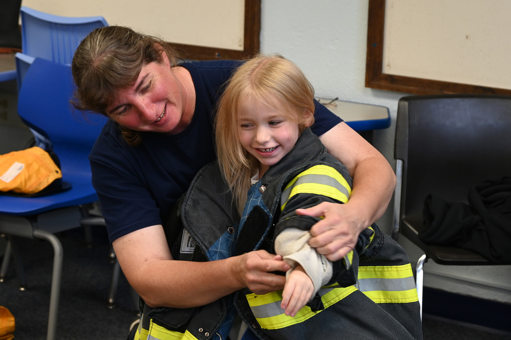 adult helping child put on fire gear