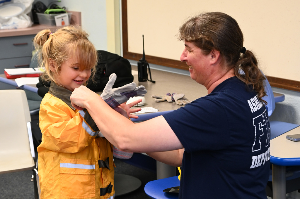 adult helping child put on dress up fire gear