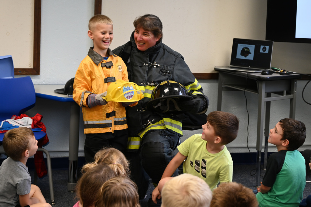 child and adult smiling wearing fire gear