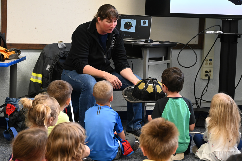 adult showing class of childern fire fighting hat