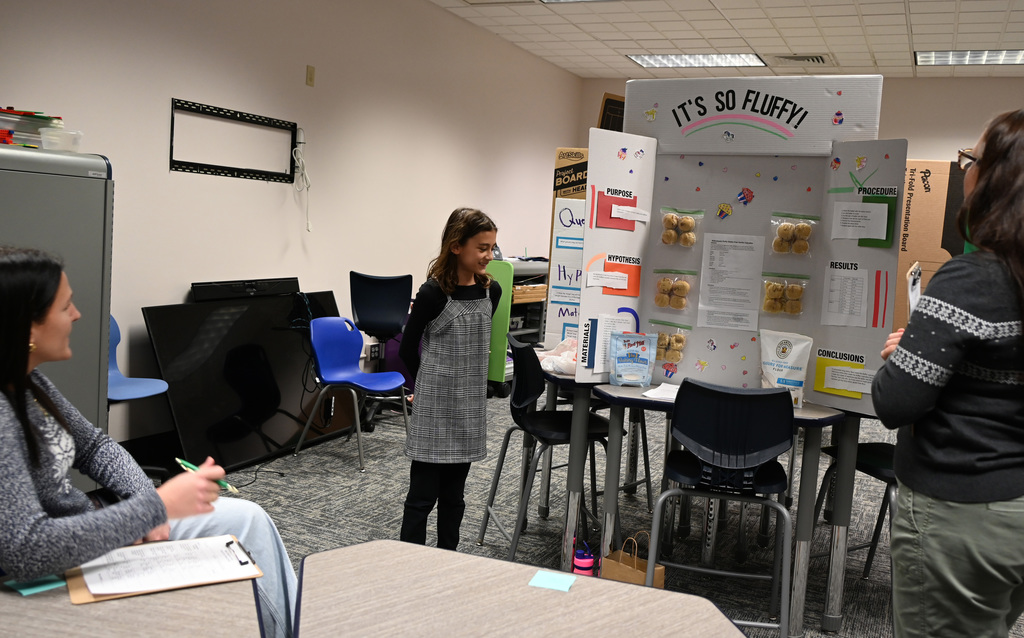 student in fornt of to judges presenting science fair project