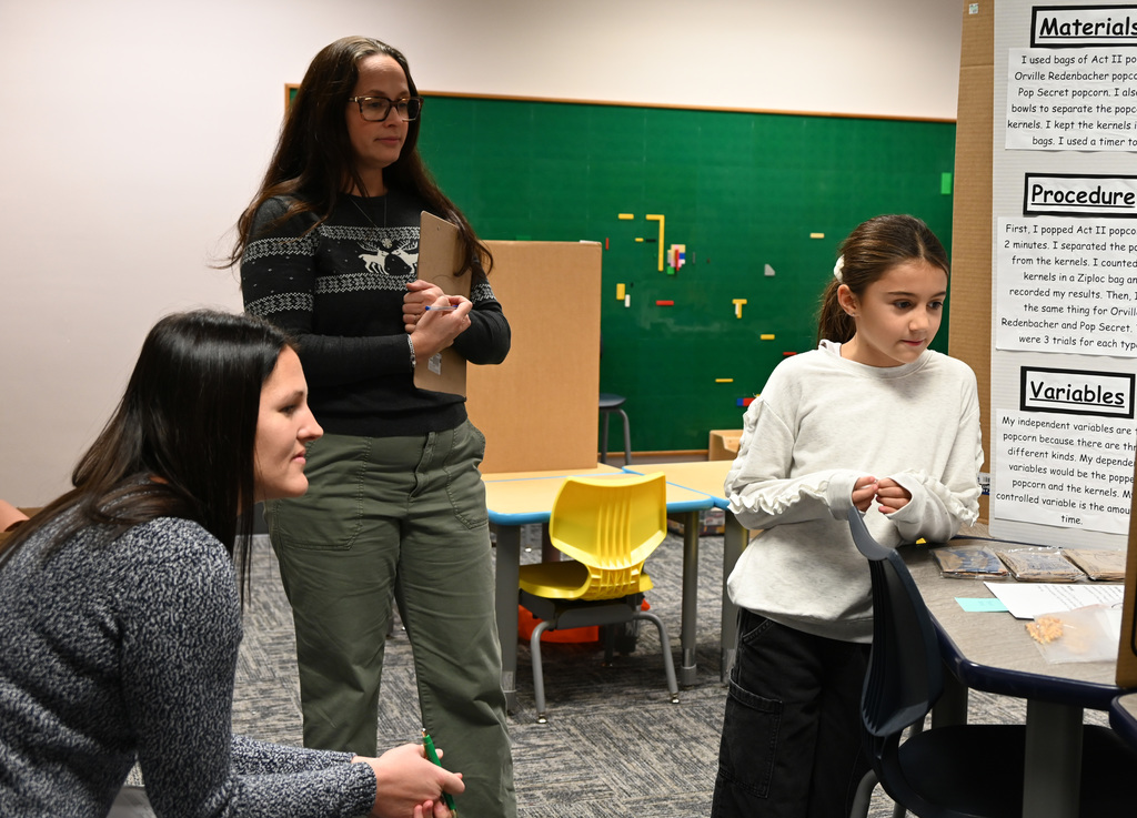 student in front of two judges presenting science fair project