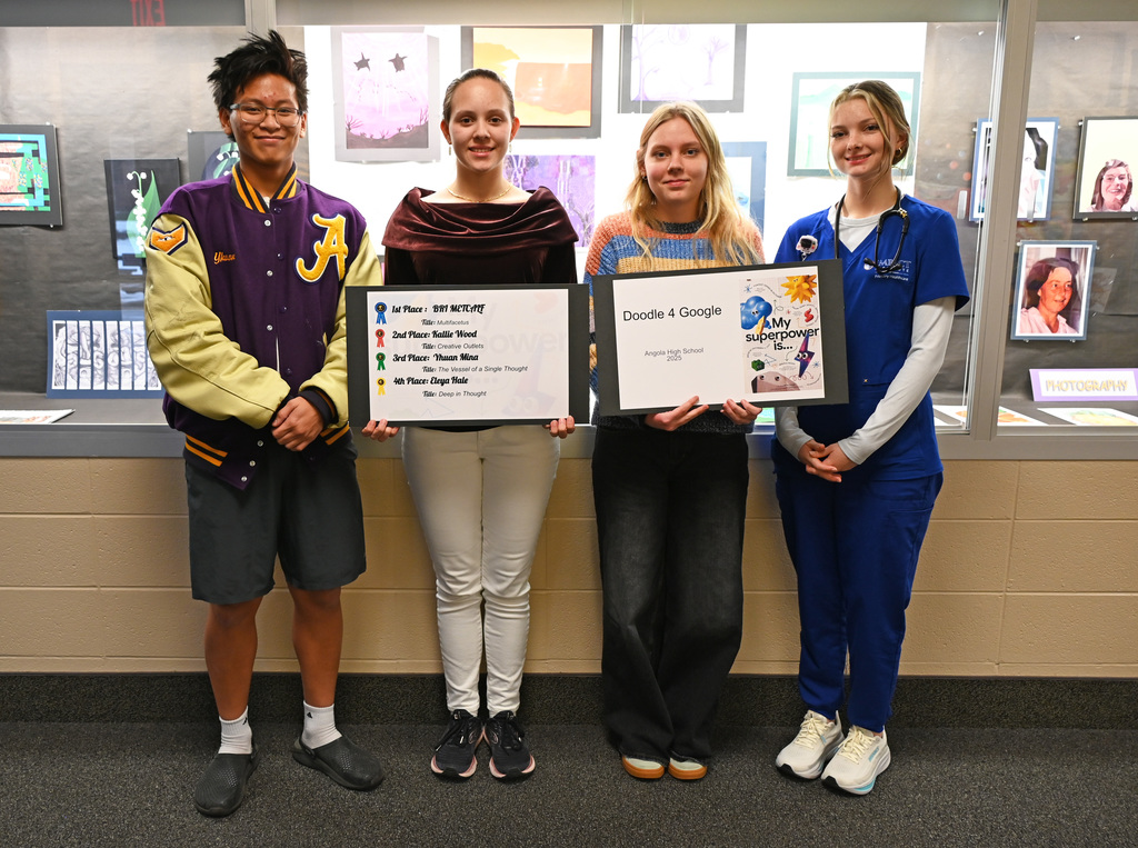 Group of 4 students standing in line holding posters