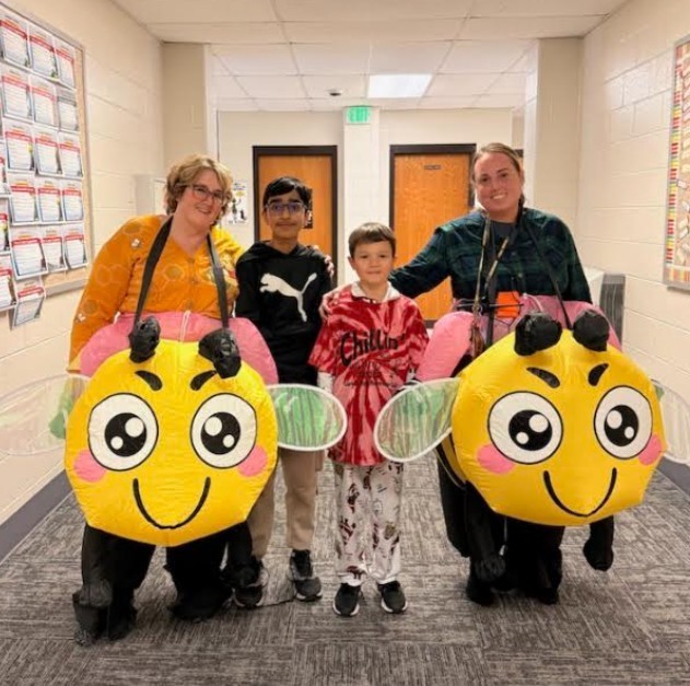 two adults in bee costumes with two students