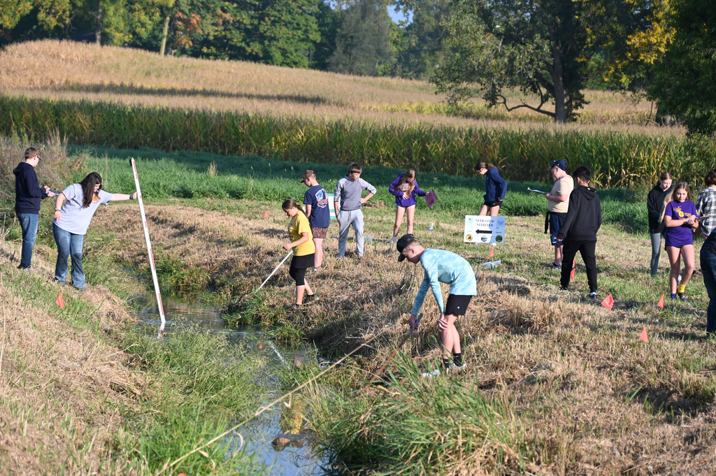 students working around a stream bed, taking water information testing