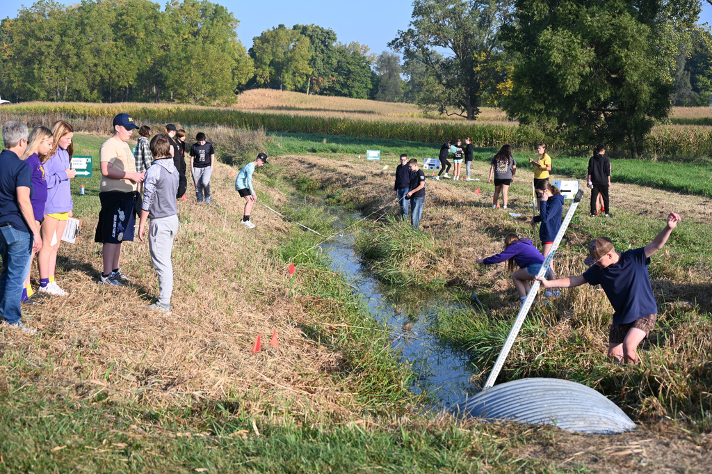 students working around a stream bed, taking water information testing