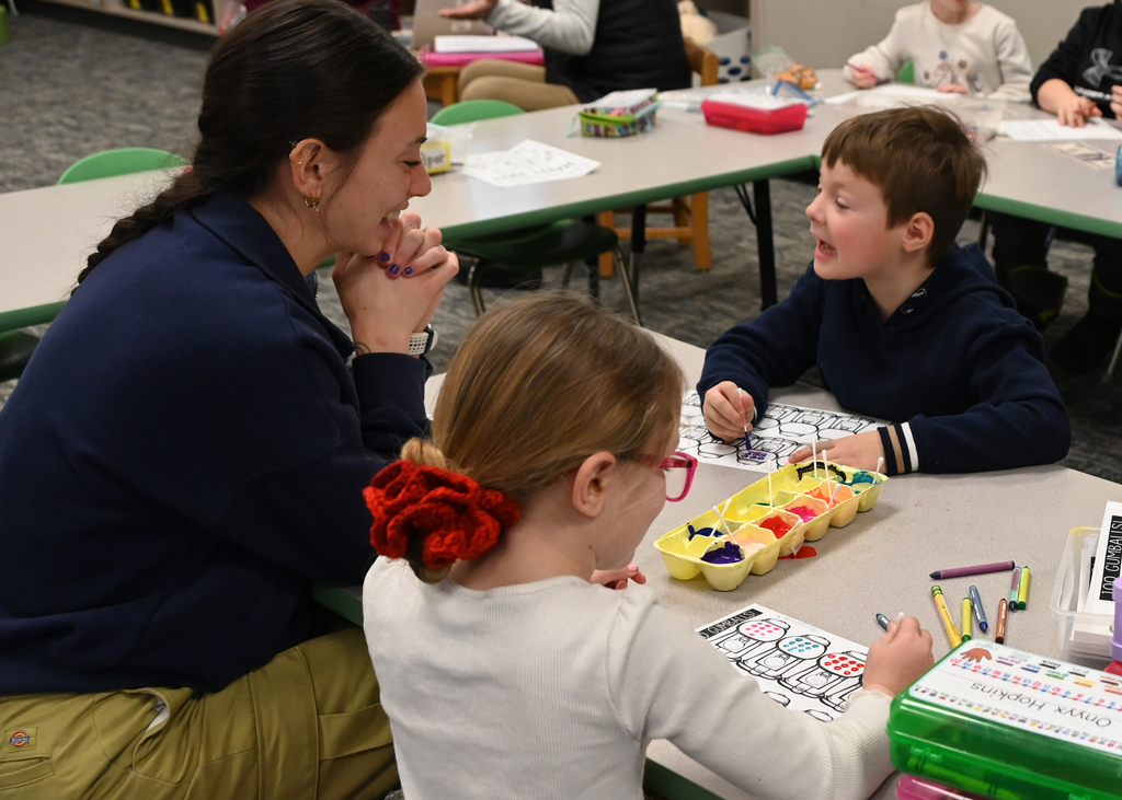 two students and teacher painting and talking and laughing