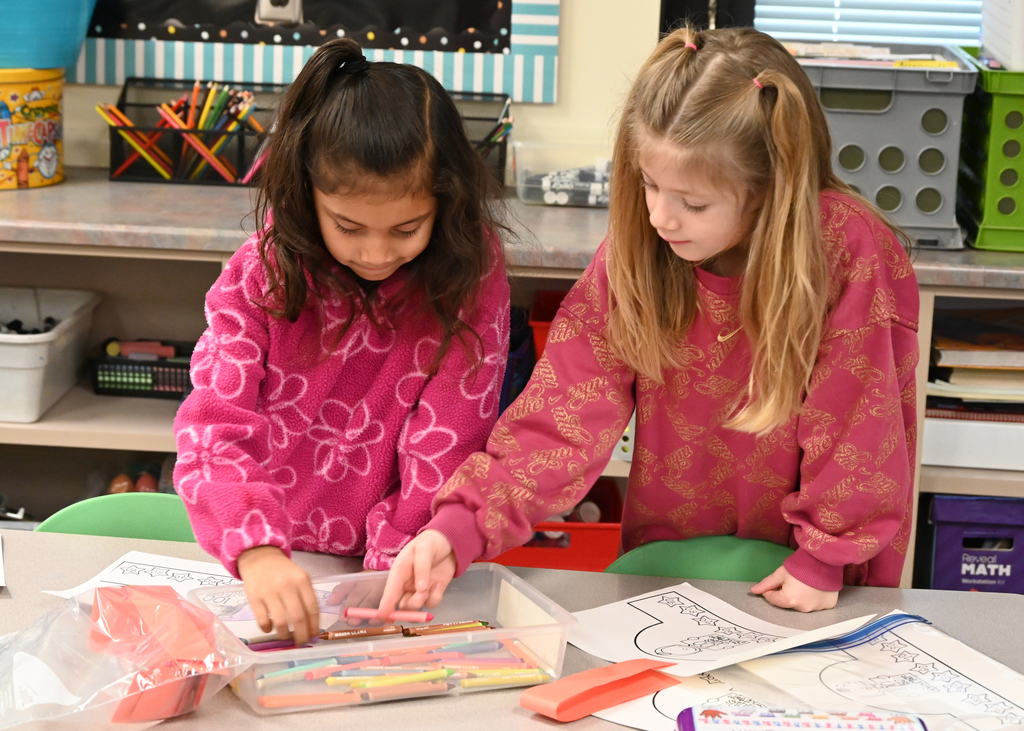 two girls getting crayons out of box