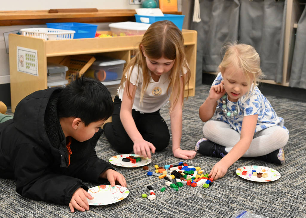 3 childern putting blocks on bricks