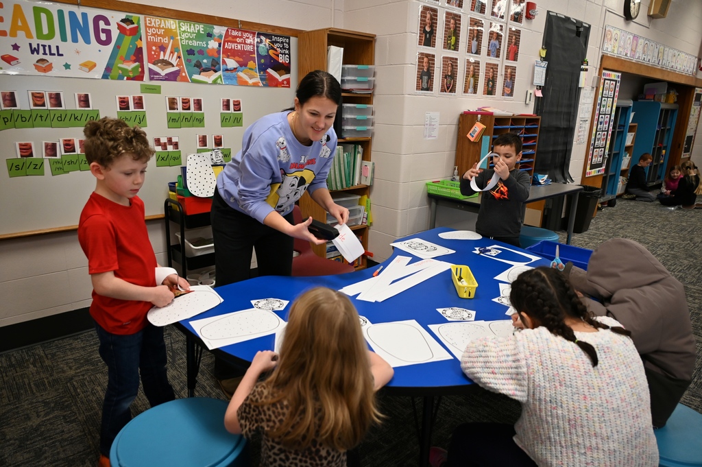 teacher at table helping 4 students with papers
