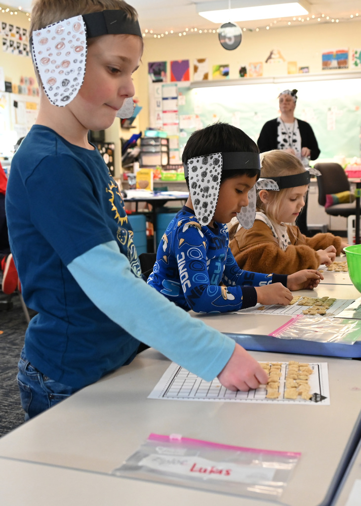 3 childern filling a graph paper with cheerios