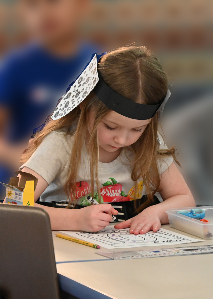 girl coloring while wearing dalmation ears