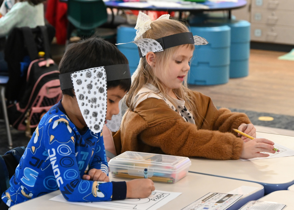 tow kids writing while wearing dalmation ears