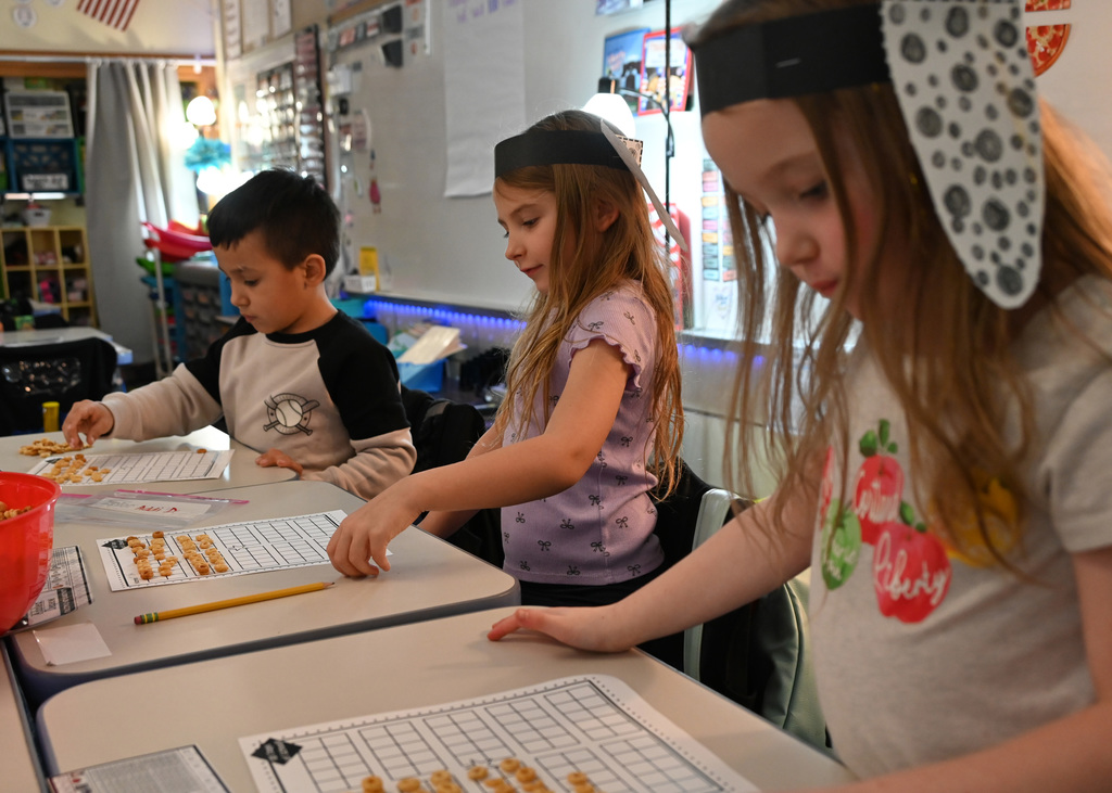 3 childern filling a graph paper with cheerios
