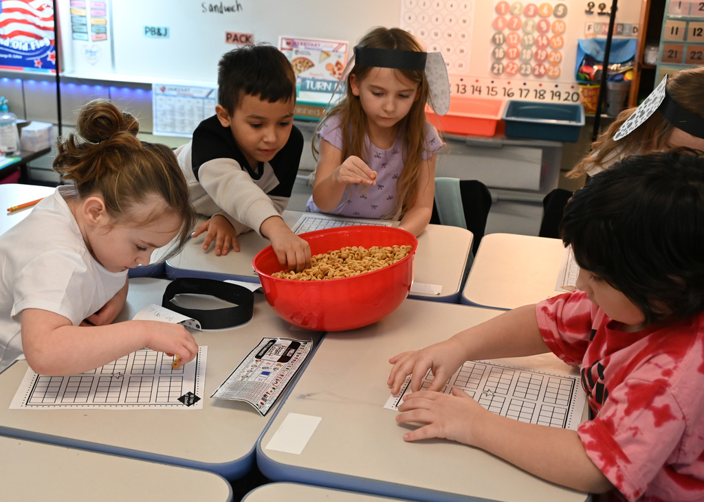 5 children getting cheerios out a bowl