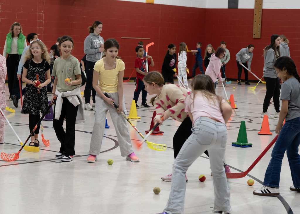 elementary students practicing hockey with stick and puck