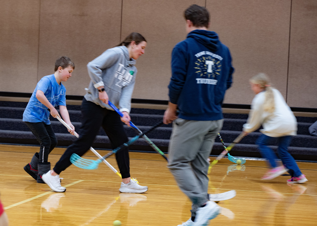 4 young people playing hockey with stick and puck