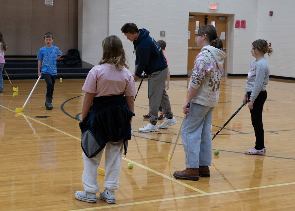 elementary students practicing hockey with stick and puck