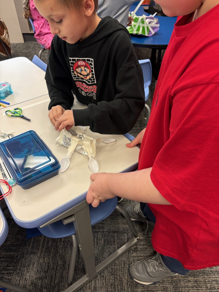 two childern looking in a conatain of water floating a hand made boat