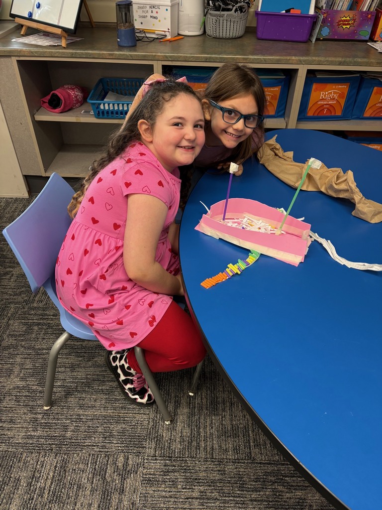 two students showing off their hand made boats