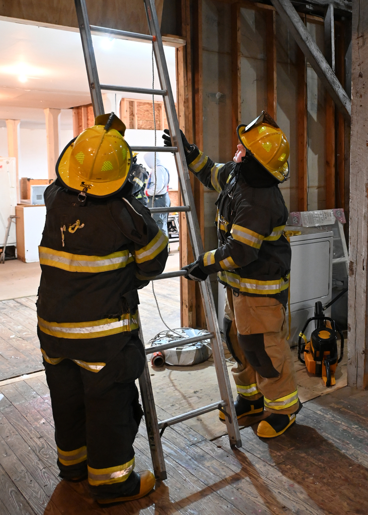 two fire fighters holding a laddet