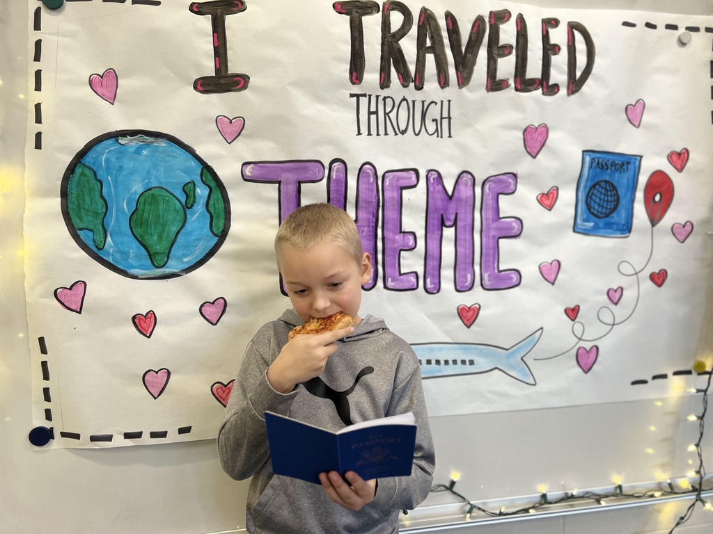 boy eating pizza as he looks a a book