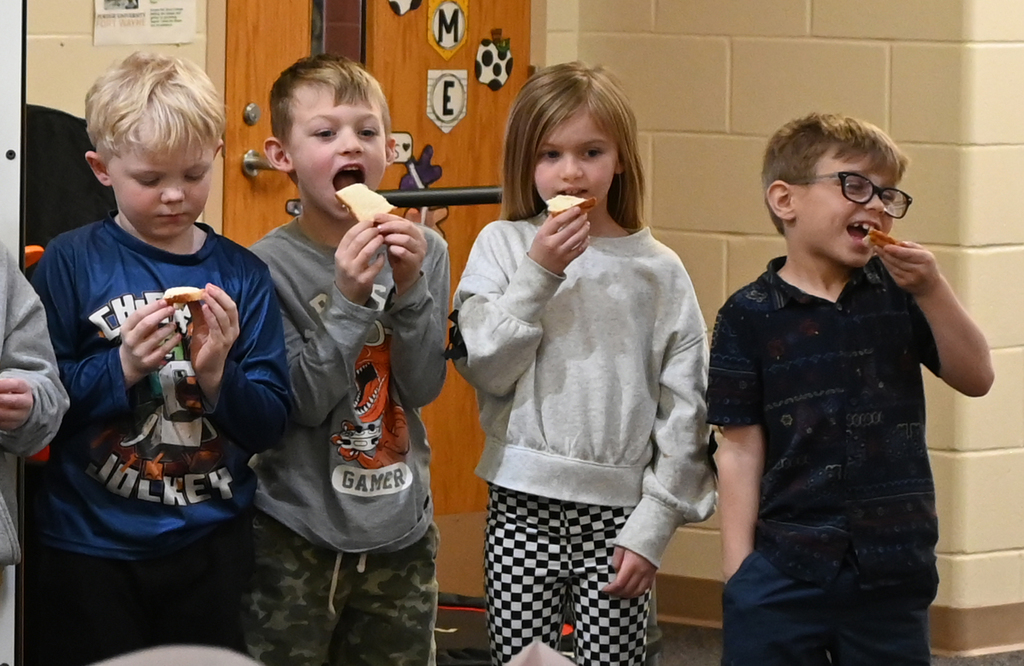 4 childern taking a bite of bread