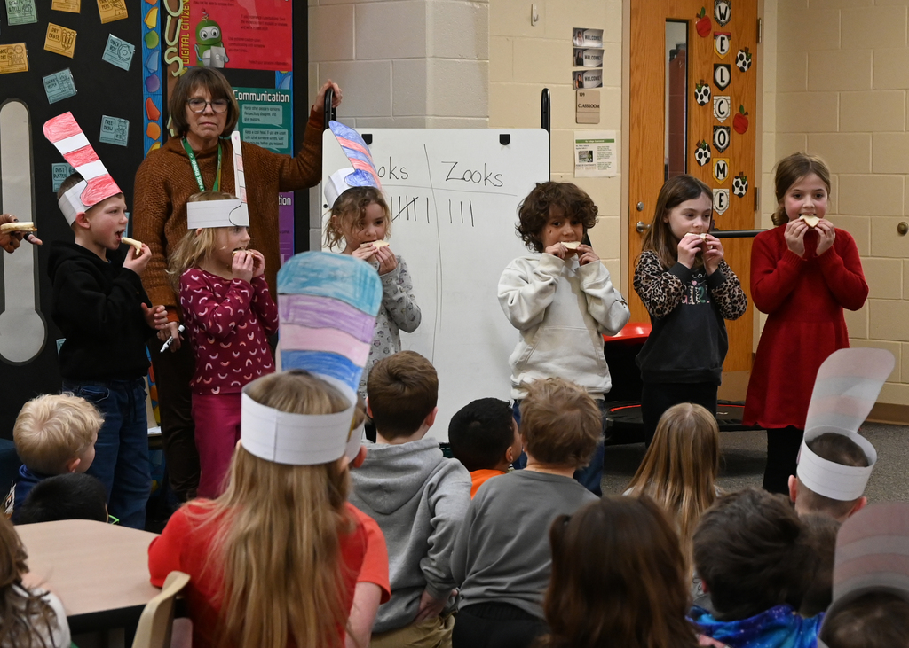 6 Students taking a bite of bread in front of class