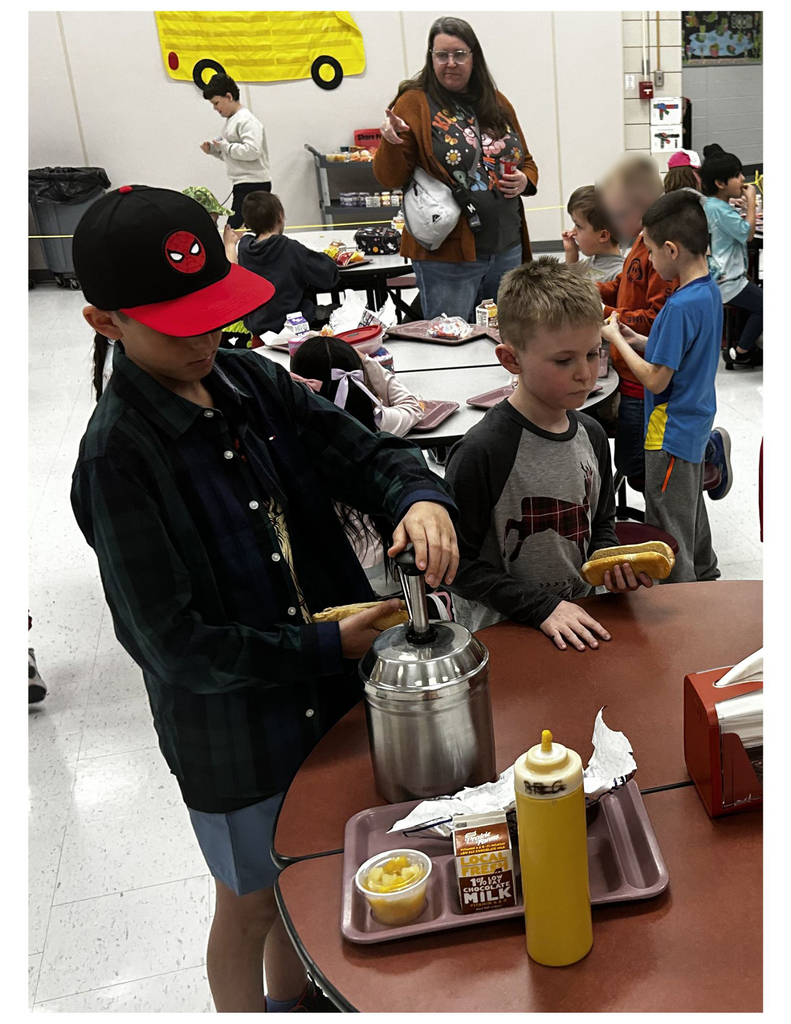 two studetns getting condiments for hot dogs in a cafeteria