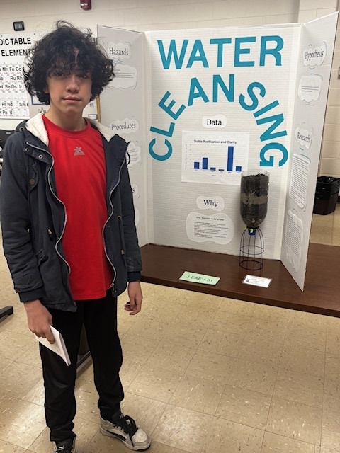 boy standing in front of poster display for science fair
