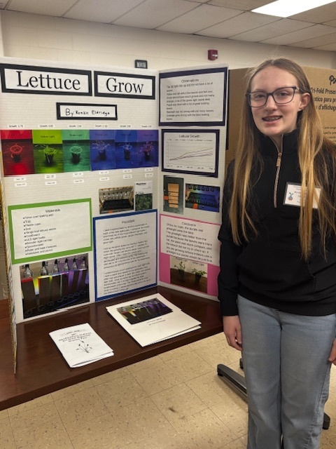 girl standing in front of poster display for science fair