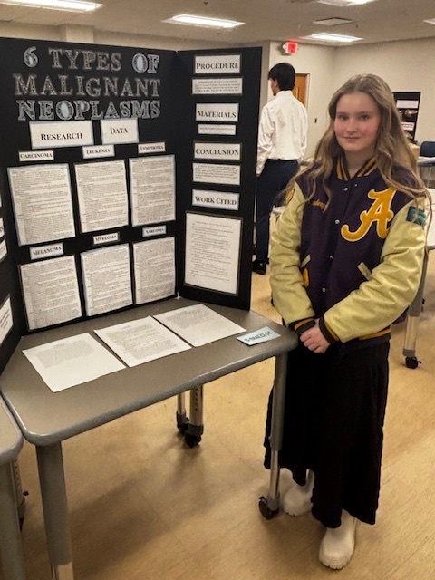 girl standing in front of poster display for science fair