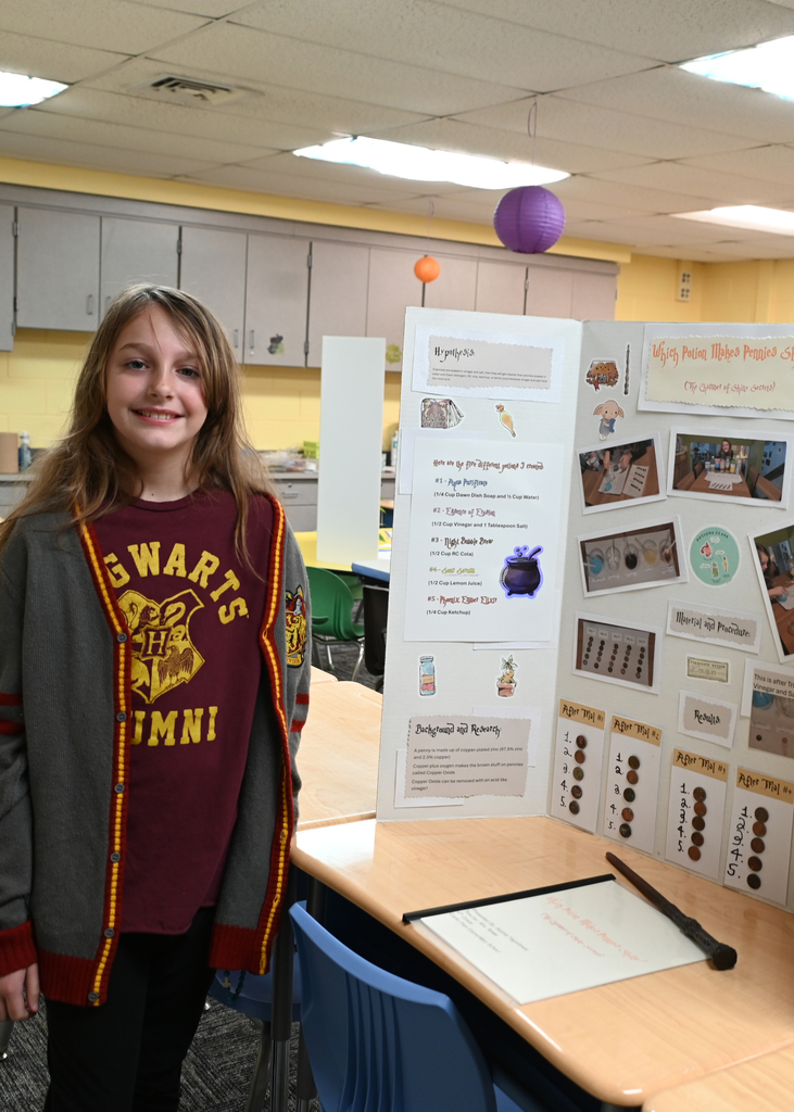 girl standing in front of poster display for science fair