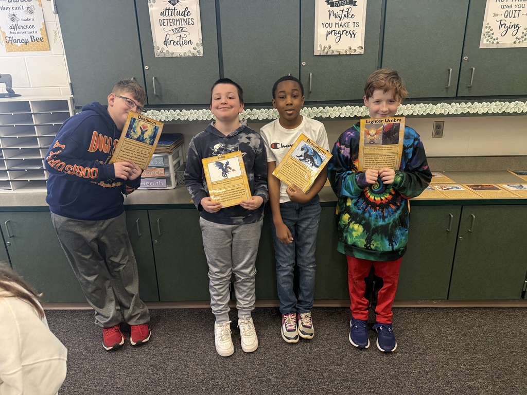 four boys standing holding self-made pokemon type cards