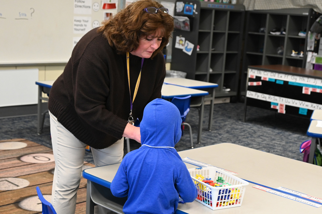 woman leaning over talking to a child wearing a blue hoodie